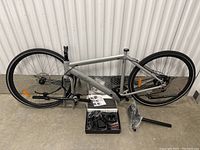 Partial assembly displaying silver frame, wheels, box of accessories and saddle post