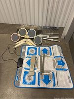 Full view of Wii drum kit components including drum pads, plastic bases, metal drumsticks, Konami dance mat, and foot pedal.