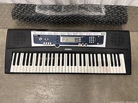 Top view of Yamaha keyboard showing 61 keys, control panel, and built-in speakers.