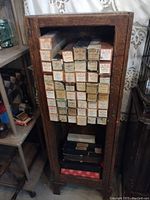 Wooden cabinet filled with stacked piano roll boxes inside, showing worn labels and original packaging.