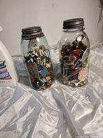 Both antique jars side by side on a fabric surface showing the variety of items inside.