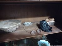 Shelf displaying the carved bone bowl, miniature leather boots, eyeglasses, and bone artifacts with a wooden background.