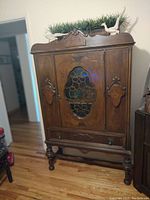 Full view of antique wooden cabinet with carved details and glass front door