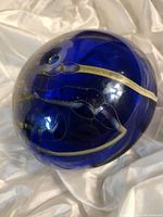 Photo showing the deep blue spherical art glass with visible bubble and abstract internal white designs and artist signature.