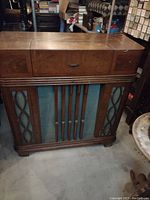 Full front view of the vintage wooden console radio with closed lid and speaker grille visible