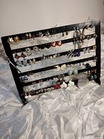 Full view of black multi-tiered earring display showing a variety of earrings with different styles and colors.