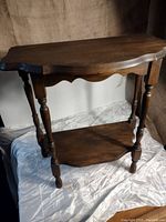 Full view of the vintage wooden table showing top, legs, and bottom shelf.