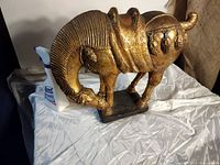 Photo showing full armadillo statue with Lysol bottle for scale, highlighting overall shape and gold textured finish.