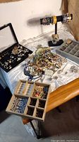 Wide angle showing assorted jewelry with necklaces, rings, bracelets, and multiple display trays on tabletop
