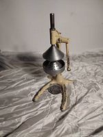 Front angled view showing the metal juicer cone and lever, mounted on a three-legged cream-colored base with scraped paint.