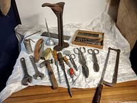 Overview of all vintage and antique tools laid out on satin fabric. Includes wrenches, hammer, screwdrivers, scissors, saw and other hand tools.