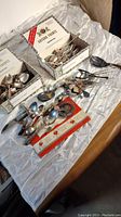Top-down view showing multiple boxes of sorted vintage cutlery filled with spoons, forks, and other utensils. Some pieces are stacked loosely beside the boxes.