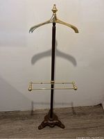 Full view of the freestanding Art Deco style coat rack showing brass handle, wood pole, brass rails and cast iron base.