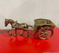 Side view of the brass horse attached to the carriage, showing size and detail.