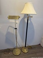 Photo showing both brass standing lamps side by side against a wall, highlighting overall appearance and scale.