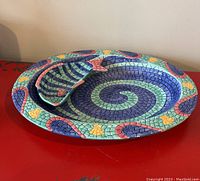 View of the chips and dip platter and fish-shaped bowl stacked showing mosaic spiral and fish design.