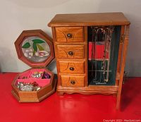 Photo showing both wooden jewelry boxes with stained glass lid on octagonal box and cabinet box with drawers and door containing jewelry
