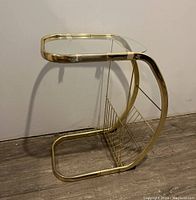 Full view of gold-tone brass C-shaped frame with removable glass top and magazine rack