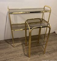 Front view of two brass frame tables with removable smoked glass shelves