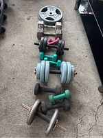 Various dumbbells and two solid 25lb cast iron weight plates on concrete floor