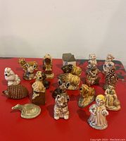 Front view of 18 Wade Whimsies porcelain figurines in various animal and character shapes on a red surface with minor visible chips.