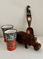 Front view showing ceramic vases with zebra patterns, ebony hippopotamus, and carved wooden spoon with giraffe detail.