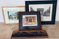 Four framed art pieces displayed together on a floor including two Paris sidewalk prints, print of Arc de Triomphe by Ducollet, and vintage farm photo on wood.