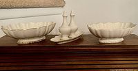 Full view of all items: two ivory scalloped serving bowls and salt & pepper shakers on tray on wooden surface