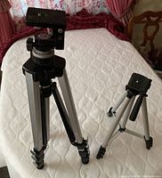 Older larger tripod model 372-839 and smaller model AT-362 shown fully extended and standing on bed surface