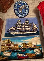 Photo of all three nautical-themed rugs arranged on carpeted floor showing oval dolphin rug, rectangular sailing ship rug, and rectangular maritime village rug.