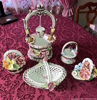 Full set of five Capodimonte ceramic decorative baskets and well displayed on a table with maroon damask tablecloth.