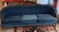 Front view of entire blue velvet tufted settee with carved wood frame