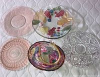 Top-down image showing all items including the grape and leaf design glass platter, the purple basket with rattan handle, and the five different crystal serving plates.