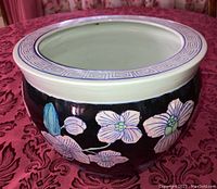 Top and side view of glazed ceramic Chinese flower pot with cream rim and black body featuring hand-painted purple flowers and green leaves.