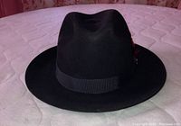 Top front view of black felt fedora hat showing overall shape and brim wide