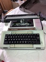 Front view of Smith Corona 2200 typewriter showing keyboard and platen with case in background.