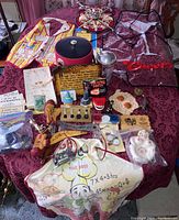 Overview of all vintage bar novelty items laid out on a purple patterned tablecloth, showing aprons, novelty teeth, shaker, cards, bottle openers, and other small items.