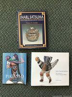 Front covers of three art books: Imari Satsuma ceramics, Picasso art book, Arctic Transformations art book showing an Inuit sculpture
