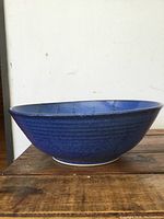 Side profile view of a blue artisan pottery bowl showing curved shape and deep cobalt glaze