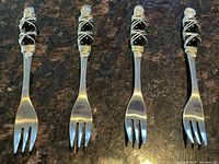 Set of 4 appetizer forks with decorative black and silver wire wrapped handles.