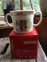 Photo showing the Bunnykins loving cup on its original red box with bunny illustration and Royal Doulton logo.
