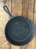 Top view of cast iron skillet showing worn cooking surface with rust and discoloration.