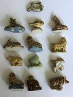 Top view of 14 assorted Wade tea animal figurines arranged on a white background showing variety of animals and ceramic detail.