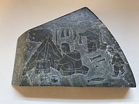 Front side of the stone etching showing a home/camp scene with tents and figures drying and cooking fish, engraved in a dark stone slab.