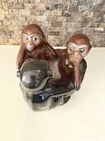 Front and side view of the combined porcelain monkeys figurines set, showing two brown monkeys and one black monkey forming a circle with gestures covering ears, eyes, and mouth.
