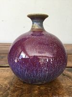 Front view of the purple and blue glazed vintage bud vase on a wooden surface.