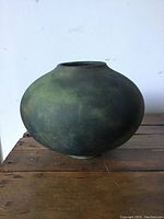 Side view of the rounded RAKU pottery vase showing the green and black muted finish and bulbous shape.
