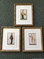Three vintage art deco fashion pictures in gold gilt frames on carpeted floor, shown together