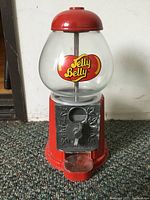 Front view of the small Jelly Belly jelly bean machine showing glass globe with logo and red metal base with coin mechanism