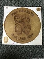 Front view of the album cover showing the circular gold medallion design with the portraits of The Beatles and the title '20 Golden Hits'. The cover shows signs of light wear and minor writing marks.